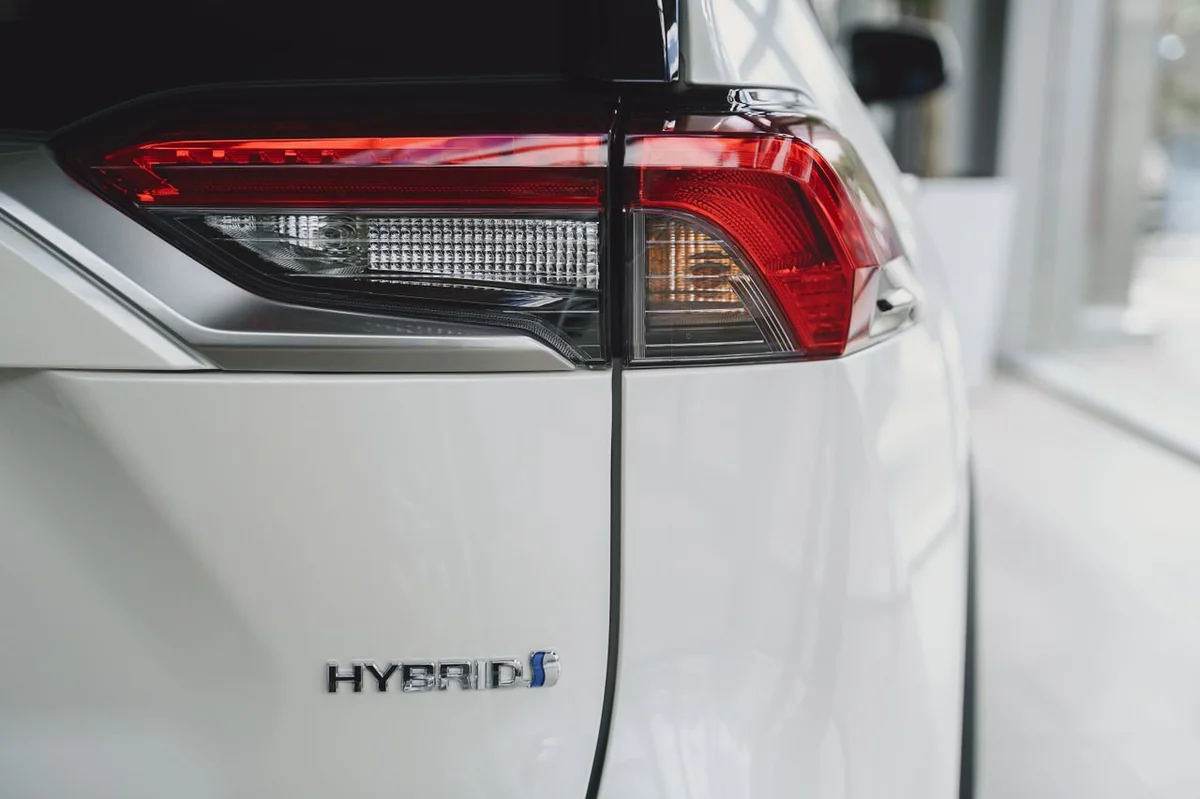 Tylne światło i emblemat „Hybrid” na białym samochodzie.